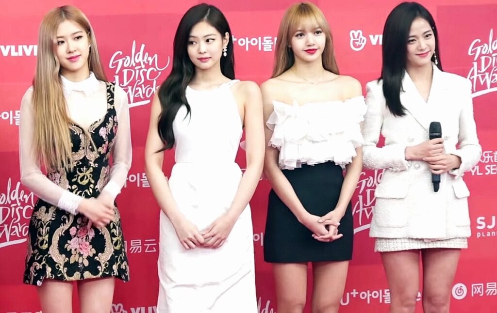 BLACKPINK members posing at a media photo zone, highlighting their status as global fashion icons and brand ambassadors.