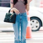 Best dressed female K-pop idols in 2026 featuring Jisoo in a casual off-duty fashion look with jeans, a striped top, and a black handbag.