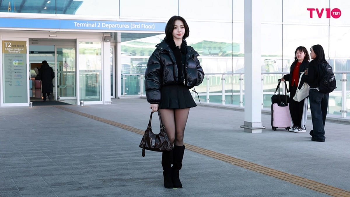 aespa Karina's iconic airport fashion featuring a glossy black puffer jacket and tall boots.